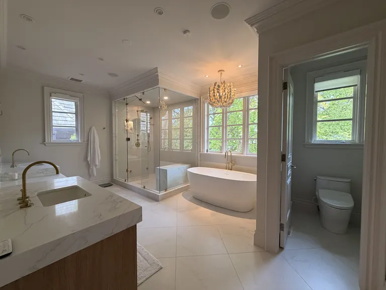 A finished bathroom with a freestanding tub under the window and a glass shower
